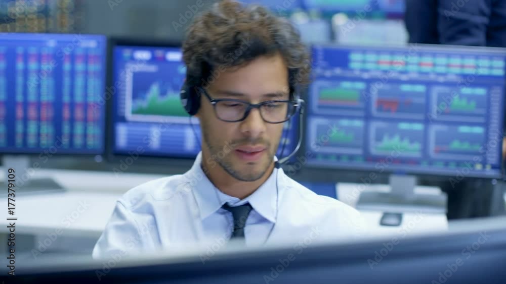 Poster broker making sales with a headset with his multi-ethnic team of stock traders at the stock exchange