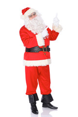 Santa Claus pointing on blank white wall, advertisement banner with copy space. Isolated on white background. Full length portrait