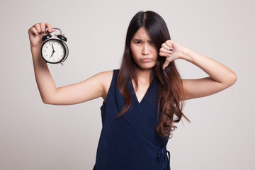 Young Asian woman thumbs down with a clock.