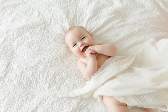 Laughing 4 month old baby on white blanket