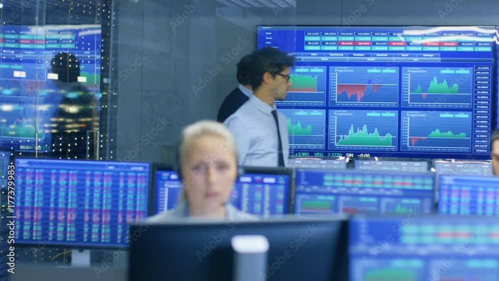 Aufkleber Stock trader Enters Office and Shakes Hands with a Colleague. Busy Office with Multi-Ethnic Team of Brokers, Dealers. Displays Show Numbers and Infographics.