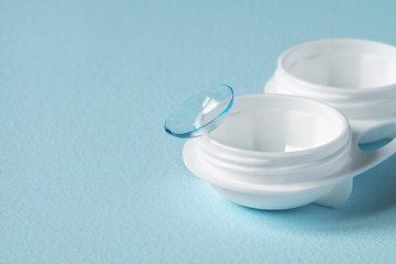 Container for contact lenses, contact lenses, on blue background. Close-up