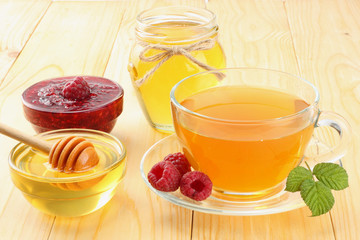 healthy background. raspberry with raspberry jam, honey and tea on light wooden background