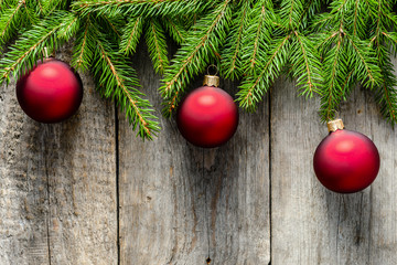 Wooden background with christmas ornaments on branches of green fir, top view