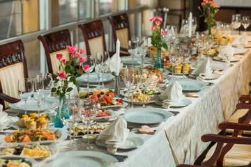 Fototapeten Beautiful festive table served for wedding celebration dinner at home or restaurant interior. Plenty of different food and cutlery. Long table covered with tablecloth and decorated with flowers. © Andrii Oleksiienko