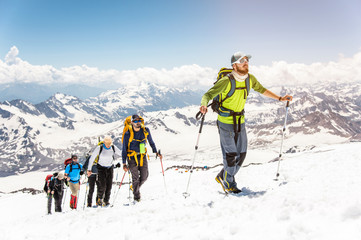 A group of mountaineers climbs to the top of a snow-capped mountain