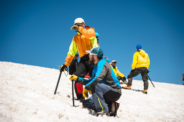 Two climbers talk on training on the right slip on the slope with an ice ax for non-stop braking