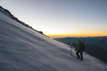 climber at sunrise early morning walks on the slope and on the ground above the snow sweeps drifting snow