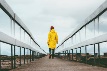 Woman walking away on bridge road Travel Lifestyle emotional concept vacations outdoor yellow...