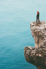 Fototapeta na wymiar Traveler standing on cliff over cold sea alone Travel Lifestyle concept outdoor. Solitude melancholy emotions