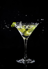 Martini splash in a cocktail glass with a zest of lime on a side