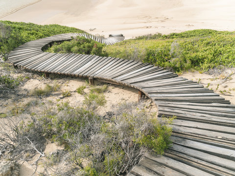 Winding wooden walkway leading to a sandy beach