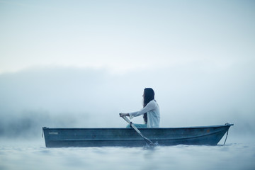 Mysterious woman in row boat on a foggy New England Morning