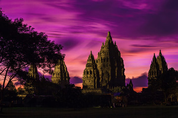 Obraz premium Candi Prambanan after sunset, illuminated from the side by the beams of searchlights. Pink sky of Yogyakarta, Jawa, Indonesia.