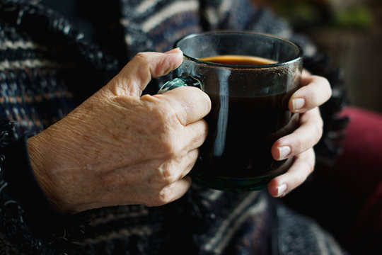 Woman holding glass mug of hot coffee