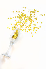 Confetti in the shape of stars poured out glasses of champagne on the white background.