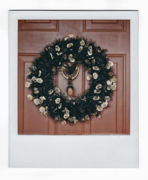 A Halloween wreath with doll head tied in the knocker.