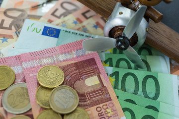 Selective focus, Euro banknotes with Euro coins with wooden toy vintage airplane as saving for travel concept