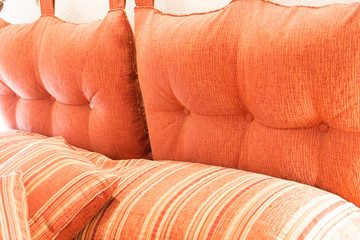 Orange cushions and pillows . Detail of a bed. Bedroom design