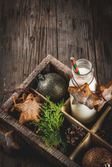 Christmas sweet and treats, Bottle with milk for Santa with gingerbread star cookies with  decoration rope and christmas decorations, in wooden box, old wooden background, copy space top view