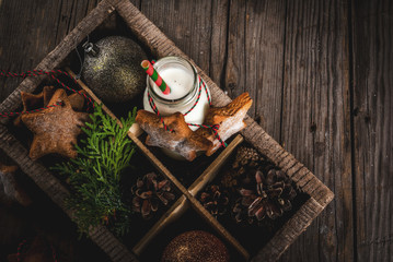 Christmas sweet and treats, Bottle with milk for Santa with gingerbread star cookies with  decoration rope and christmas decorations, in wooden box, old wooden background, copy space top view