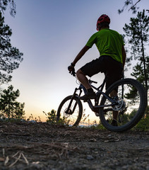 Fototapeta premium Mountain biker looking at sunset, bike trail in autumn mountains