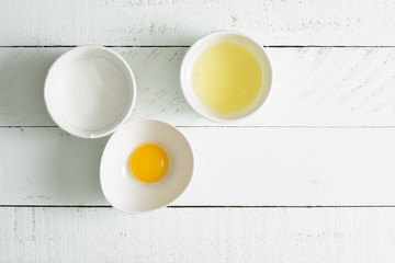 Baking ingredients- sugar, egg white, egg yolk on wooden board.