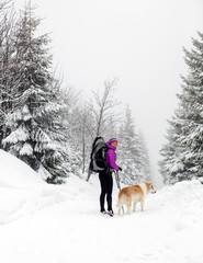 Fototapeta na wymiar Happy woman walking in winter forest with dog
