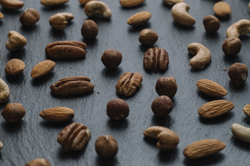 Variety of mixed nuts - almond, hazelnuts and cashew - on the dark slate background with copy space. Top view. Toned
