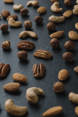 Variety of mixed nuts - almond, hazelnuts and cashew - on the dark slate background with copy space. Top view. Toned