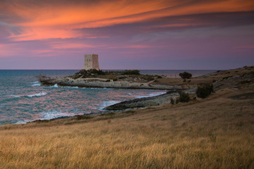 Dramatic sunset on the Molinella beach near Vieste, Italy, with old defense tower.