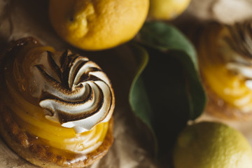 Lemon pie on the table with citrus fruits. Traditional french sweet pastry tart. Delicious, appetizing, homemade dessert with lemon cream. Copy space, closeup. Selective focus. Toned - 177403177
