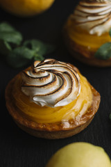 Lemon pie on the table with citrus fruits. Traditional french sweet pastry tart. Delicious, appetizing, homemade dessert with lemon cream. Copy space, closeup. Selective focus. Toned
