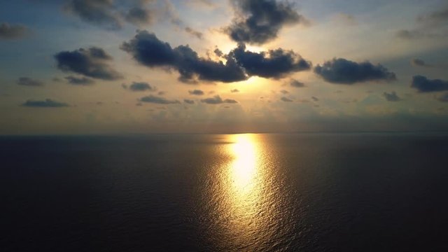 Sunset over the ocean with sunrays behind the clouds. Beautiful cloudscape and sunset breaking through cloud above the sea. 4K Aerial Footage.