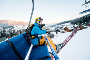 Skier man sitting at ski chair lift in beautiful day looking and thoughtfully into the distance. Close-up. Concept of skiing