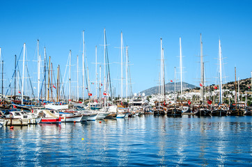 Fototapeta na wymiar Large and small beautiful yachts are reflected in the sea water in the port of Bodrum, Turkey.