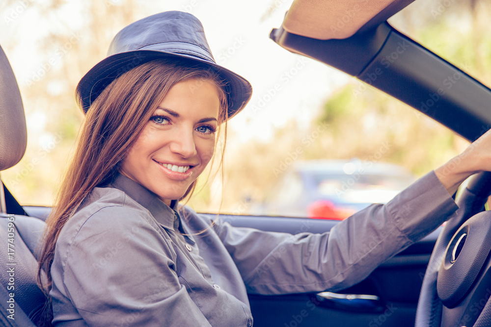 Wall mural Happy young woman driving convertible on sunny day