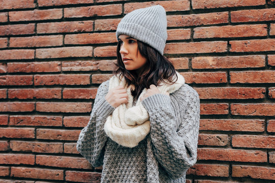 Portrait of girl with winter clothes on brick wall.