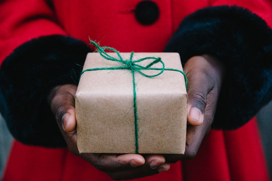 African American girl's hand in red coat holding a wrapped present