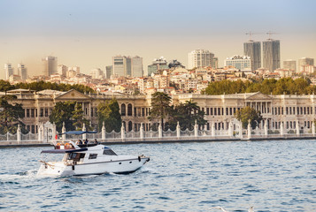 A beautiful luxury yacht runs along the waters of the Bosphorus against the backdrop of the sights of Istanbul
