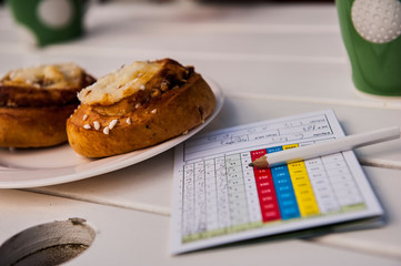 Golf Scorecard and pen on table with cinnamon rolls in a café