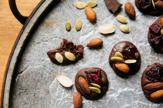 Chocolate with cranberry, almonds and pumpkin seeds on a stone tray from above