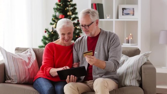 happy senior couple with tablet pc at christmas
