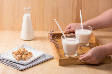 Dairy products. A bottle of milk and glass of milk serve with almond candies on a wooden table.