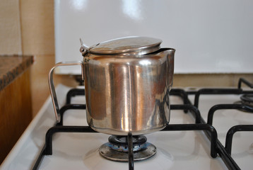 Heating up water in stainless steel cooker on gas burning stove.