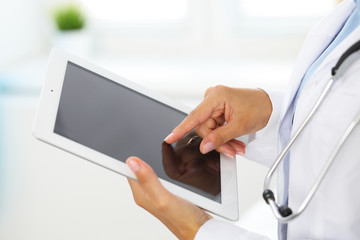 Woman doctor using tablet computer while standing straight in hospital