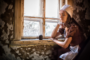 sad woman in a rustic dress sitting near window in old house feel lonely. Cinderella style