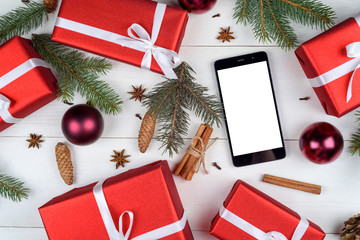 Mobile smart phone with blank screen for app presentation with Christmas decorations, copy space. Christmas gifts on wooden background . Flat lay, top view. Christmas application mock up template 