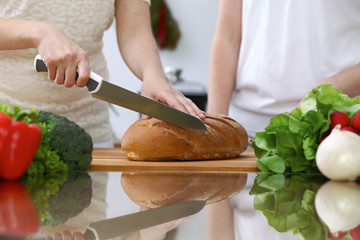 Close-up of human hands slicing bread in a kitchen. Friends having fun while cooking in the kitchen. Chef cook represent culinary masterclass
