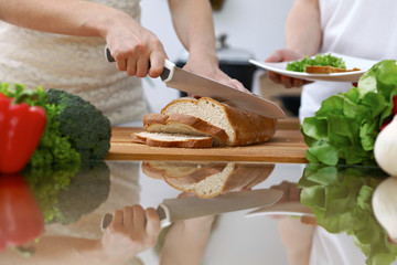 Close-up of human hands slicing bread in a kitchen. Friends having fun while cooking in the kitchen. Chef cook represent culinary masterclass